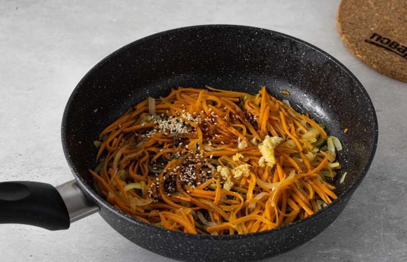 1. Этап. Салат из соленого папоротника по-корейски: Добавьте в сковороду соевый соус, острый и черный перец, измельченный чеснок и кунжут.