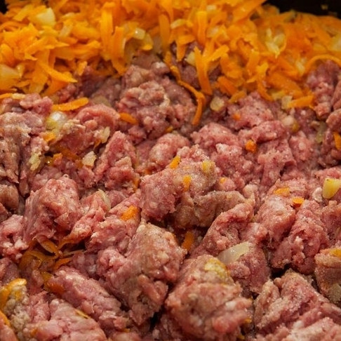 1. Этап. Лазанья с мясом: Добавляем в жаровню говяжий фарш, разминаем его лопаткой, перемешиваем с овощами.