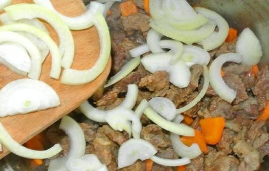 1. Этап. Мясо с морковью: Чистим лук и нарезаем полукольцами. Добавляем на сковородку и обжариваем с мясом и морковкой минут 5.