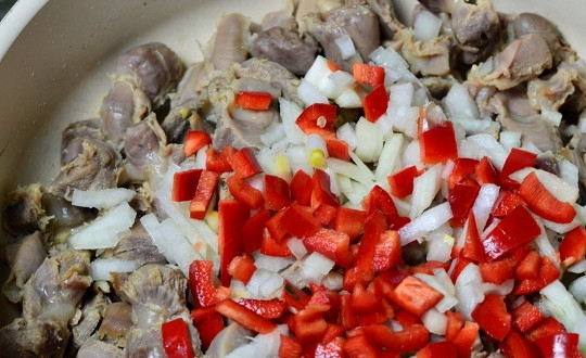 1. Этап. Рагу из куриных желудков: 2. Аккуратно слейте воду и выложите субпродукты на сковороду с разогретым растительным маслом. Добавьте измельченный лук и сладкий перец. Можно также добавить морковь. Оставьте томиться на среднем огне, периодически помешивая.