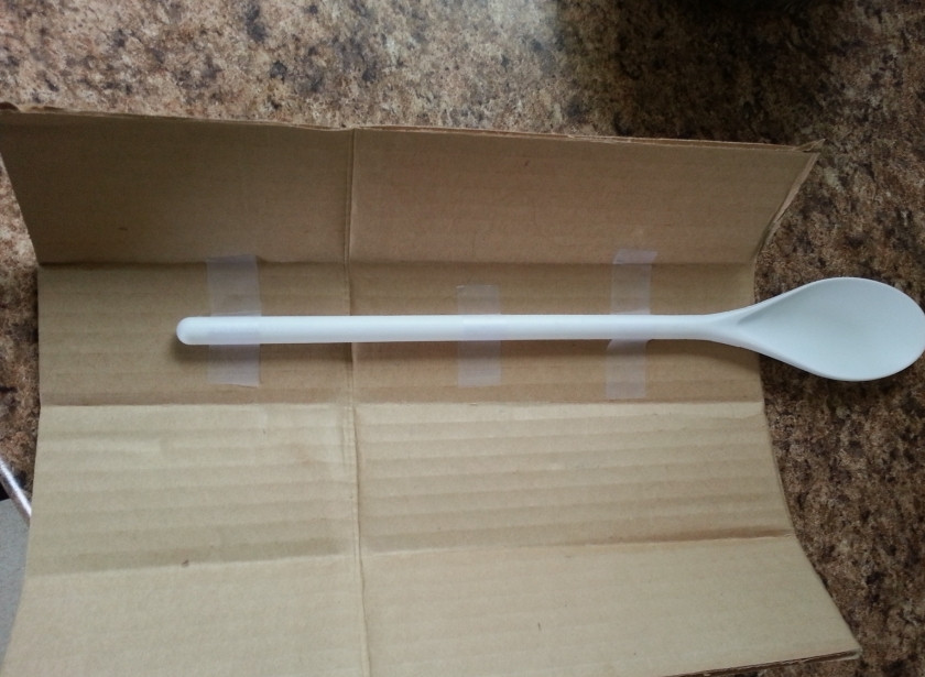 1. Этап. Яйца в форме сердечек: На картон положите пластмассовую ложку. Закрепите скотчем.