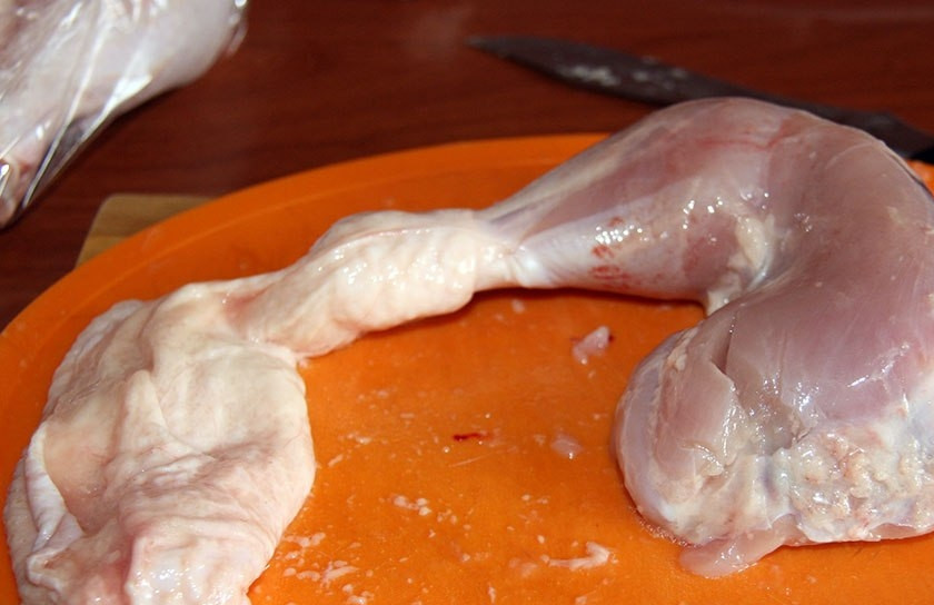 1. Этап. Фаршированные куриные окорочка без кости: Для начала окорочка хорошо промываем. Затем мнимите кожу с окорочков. Отрубите кость внизу ножки. Далее отделите кость от филе.