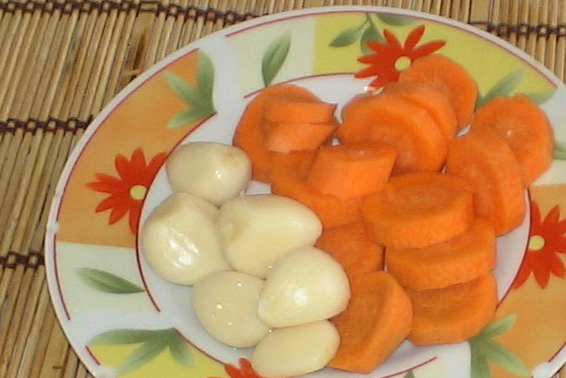 1. Этап. Закатка огурцов с лимонной кислотой: Также кладем в банки зубчики чеснока и морковь, порезанную кружочками.