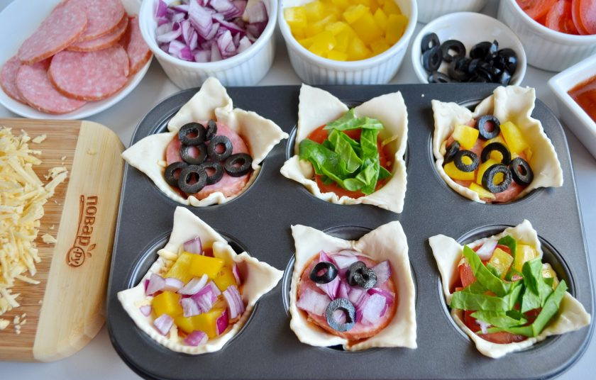 1. Этап. Закуска Пицца в стаканчиках: А теперь положите разные начинки, пусть работает ваша фантазия. Я сделала такие комбинации: колбаса, оливки; помидор, шпинат; колбаса, сладкий перец, оливки; колбаса, лук, оливки; помидор, сладкий перец, шпинат. Сверху снова по щепотке сыра и в духовку на 15 минут, температура 220 градусов.