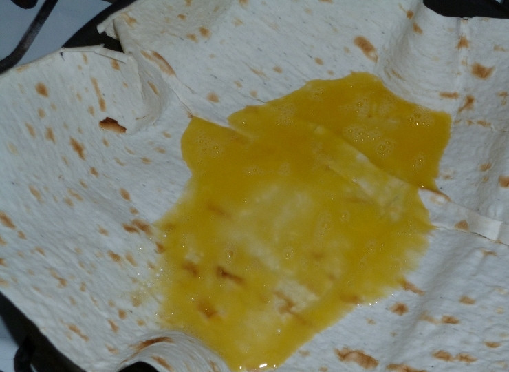 1. Этап. Ёка: Когда лаваш прогреется, вылейте на него яйцо.