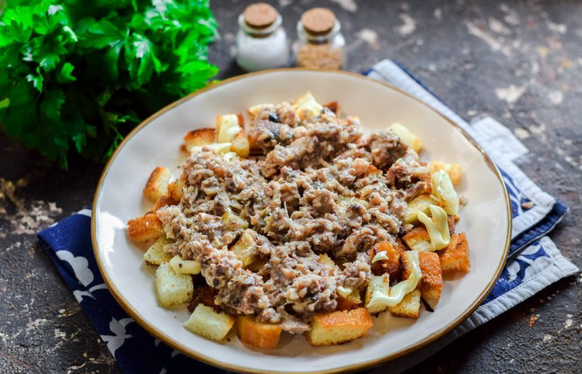 1. Этап. Салат Одуванчик с рыбными консервами: Консервы разомните и выложите поверх сухариков.