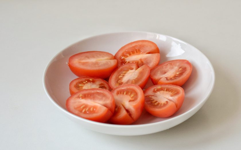 1. Этап. Помидоры с базиликом на зиму: Нарежьте помидоры половинками, плодоножку удалите.