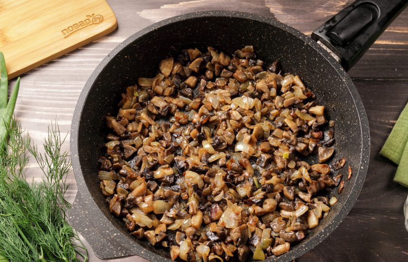 1. Этап. Салат с курицей, грибами и маринованными огурцами: Лук нарежьте кубиками и обжарьте до мягкости, затем добавьте нарезанные шампиньоны и готовьте до испарения жидкости. В конце добавьте соль по вкусу.