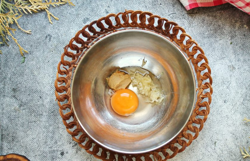 1. Этап. Соус для салата Цезарь без анчоусов: Разделите яйцо на белок и желток. Желток выложите в миску, белок не понадобится. Добавьте к желтку горчицу и измельченный чеснок.