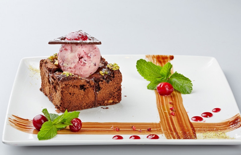 1. Этап. Брауни с клюквенным мороженым: 5. Охладить. Разрезать на квадраты. Украсить шоколадным ганашем, шариком клюквенного мороженого и веточкой мяты.