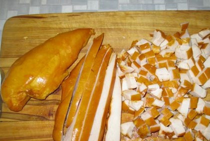 1. Этап. Салат Подсолнух с курицей: Сначала возьмите копченую куриную грудинку и порежьте ее на мелкие кусочки. Выложите кусочки на дно салатницы.