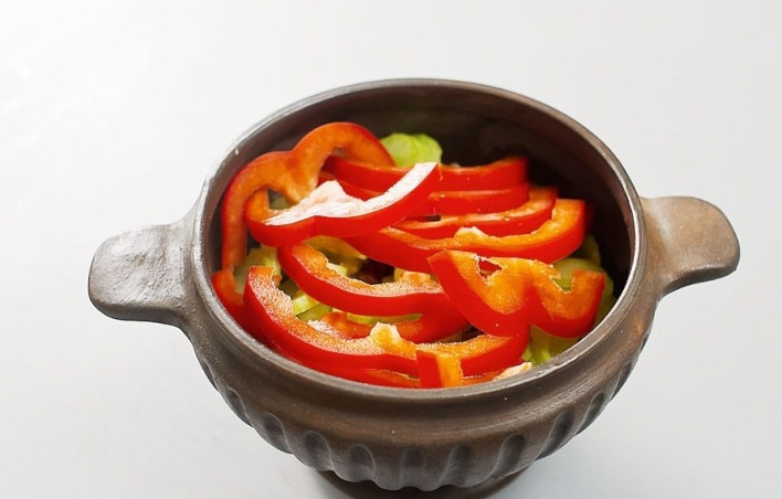 1. Этап. Телятина в горшочках: Перец болгарский порежьте полукольцами и добавьте поверх сельдерея в горшочек.