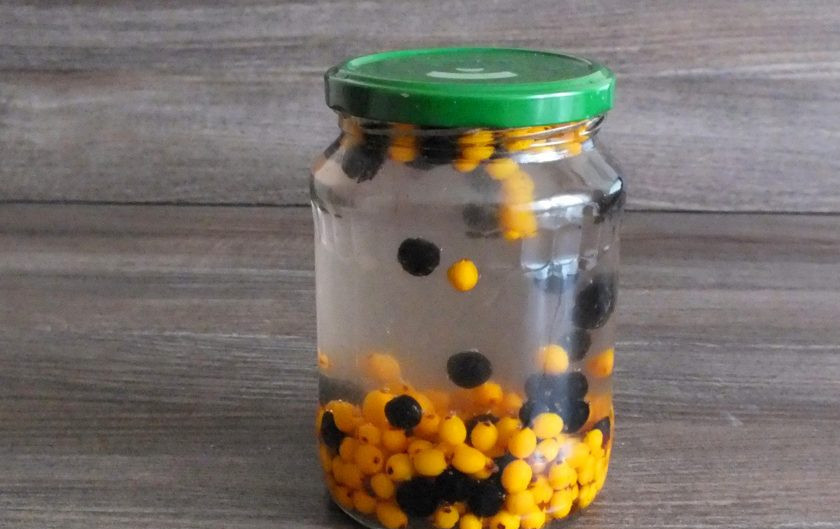 1. Этап. Компот из облепихи и черноплодной рябины: Переложите ягоды в чистую, стеклянную тару. Залейте крутым кипятком. Прикройте крышкой и оставьте на 20 минут.