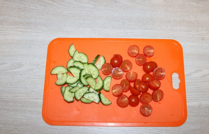 1. Этап. Салат с куриной грудкой и помидорами: Огурцы нарежьте полукольцами, помидоры черри на половинки.