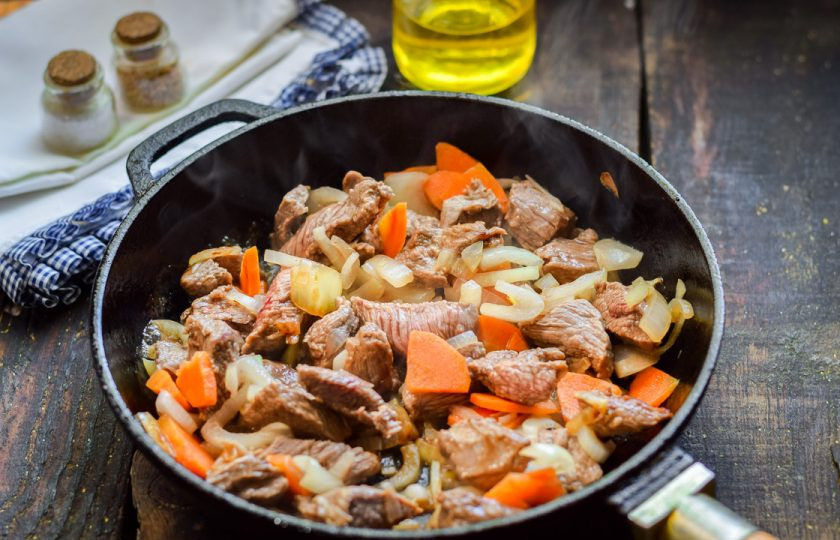 1. Этап. Перловка с мясом и грибами: В сковороде прогрейте масло, выложите овощи и мясо. Жарьте на умеренном огне 5-7 минут.