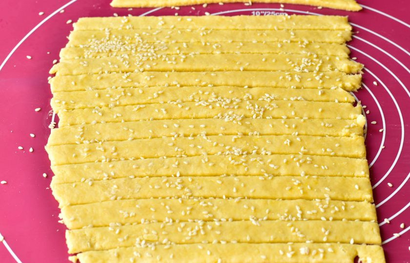 1. Этап. Сырные хрустики: Сверху посыпьте полосочки кунжутом, немного его придавите рукой.