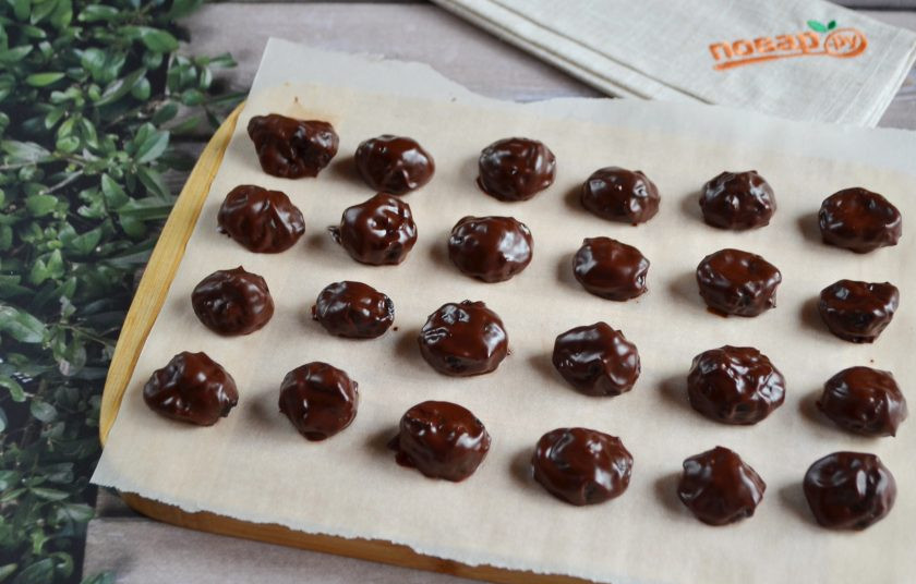 1. Этап. Конфеты Чернослив в шоколаде: 6. Разделочную кухонную доску (или поднос) застелите пергаментной бумагой и выкладывайте на неё готовые конфеты. После того, как все черносливины будут в шоколаде, уберите лакомство в холодильник на 1 час для застывания.