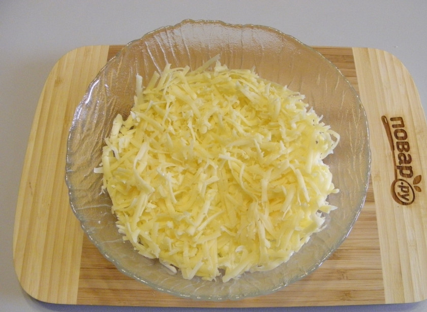 1. Этап. Салат Мимоза новогодний: Второй слой салата - тертый сыр. Распределите его равномерно.