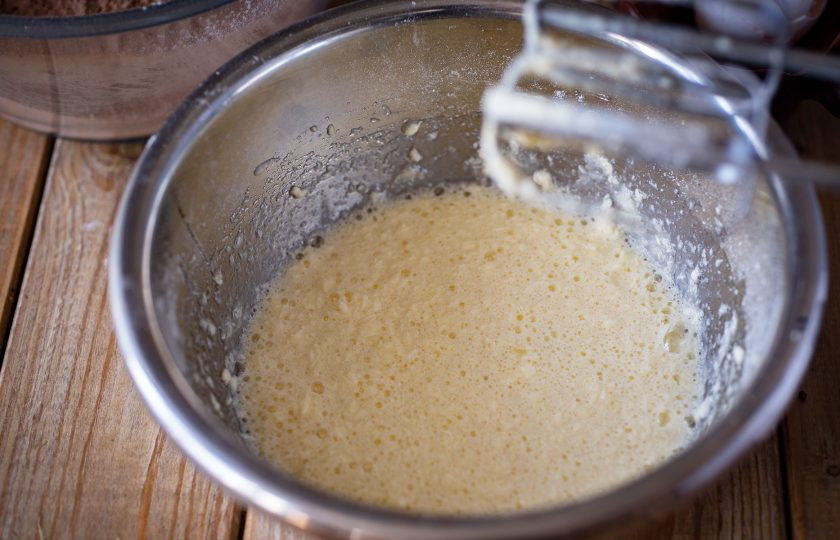 1. Этап. Шоколадное треснутое печенье: Вбейте яйца и вмешайте миксером их в масляную смесь.