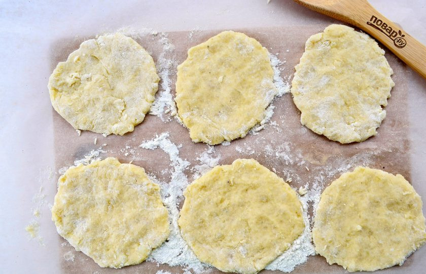 1. Этап. Картопляники с постной начинкой: Рабочую поверхность присыпьте мукой. Тесто разделите на две части, скатайте из них колбаски, разрежьте на 12 частей. Каждую раскатайте в лепешку.