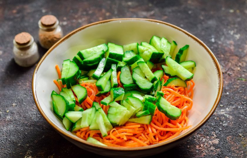 1. Этап. Салат Муравейник с корейской морковью: Свежий огурец сполосните и просушите, нарежьте дольками и добавьте в салат.