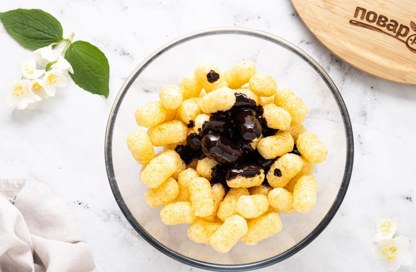 1. Этап. Десерт из кукурузных палочек: Кукурузные палочки пересыпьте в глубокую миску. Их можно предварительно нарезать или оставить целыми. Влейте растопленный шоколад с маслом.