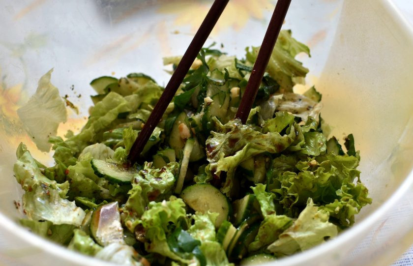 1. Этап. Освежающий салат из огурцов с арахисом: Полейте салат заправкой и легко перемешайте. Удобно это делать палочками, так овощи не мнутся.