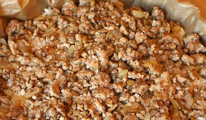 1. Этап. Слоеный пирог-перевертыш: Фарш обжариваем с измельченным луком и кладем поверх риса. Разравниваем.