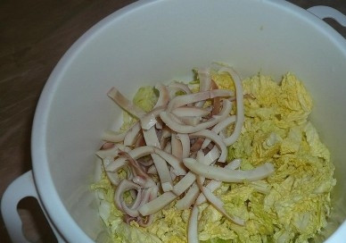 1. Этап. Салат из кальмаров и пекинской капусты: Выкладываем в емкость капусту, добавляем к ней полоски кальмара.