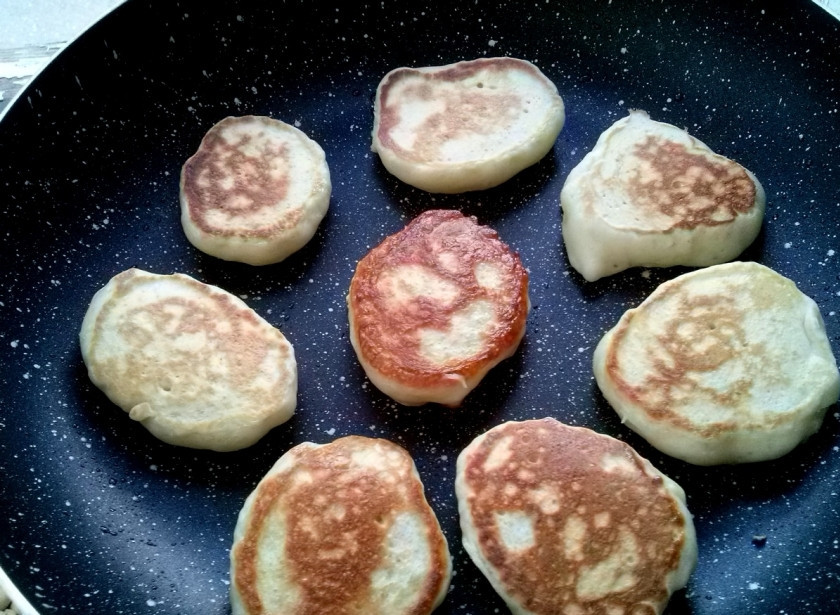 1. Этап. Оладьи на молоке с дрожжами: Поставьте сковороду на средний огонь, смажьте ее растительным маслом. Тесто не перемешивайте! Берите аккуратно столовой ложкой по стенке миски и выкладывайте на сковороду. Обжарьте оладьи с двух сторон до румяности.