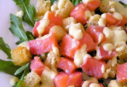 1. Этап. Салат Цезарь с семгой: Затем выложите гренки и нарезанную небольшими кубиками семгу, полейте соусом.