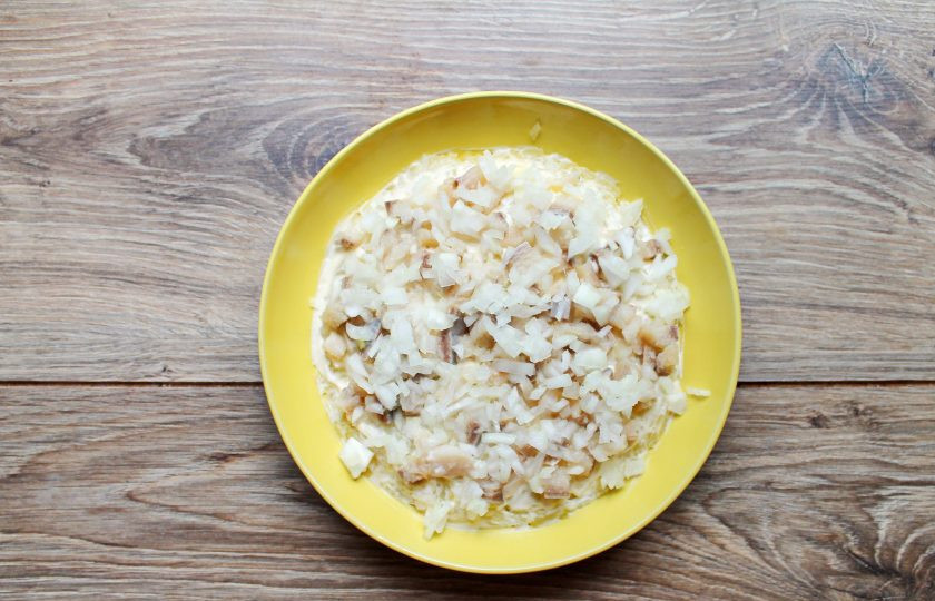 1. Этап. Селёдка под шубой с двумя видами рыбы: Репчатый лук очистите и мелко порежьте. Филе сельди мелко порежьте и смешайте с луком, выложите поверх картофельного слоя. Смажьте сельдь с луком майонезом.