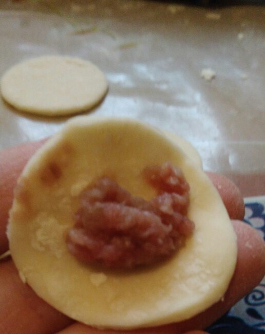 1. Этап. Пельмени из говяжьего фарша с луком: 5. Теперь в каждую часть добавляем фарш, слепливаем плотно тесто и сворачиваем к середине, чтобы получить привычную форму пельменей.