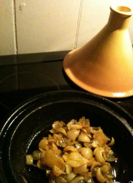 1. Этап. Куриные крылышки с бататом и черносливом: 1. Налейте 2 столовые ложки масла в жаропрочную керамическую емкость с крышкой или жаровню и поставьте на медленный огонь. Добавьте лук, порезанный тонкими полукольцами, влейте 1 столовую ложку воды, посолите, накройте емкость и томите около 30 минут, изредка помешивая, пока лук не станет очень мягким, но не поменяет цвет.