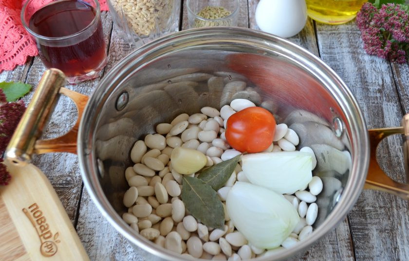 1. Этап. Перловая каша с фасолью, тыквой и беконом: Фасоль вымойте и переберите. Положите ее в кастрюлю с зубчиком чеснока, лавровым листом, половинкой луковицы, помидором. Залейте чистой водой и варите до мягкости, солить не нужно. В конце варки удалите овощи и лавровый лист.