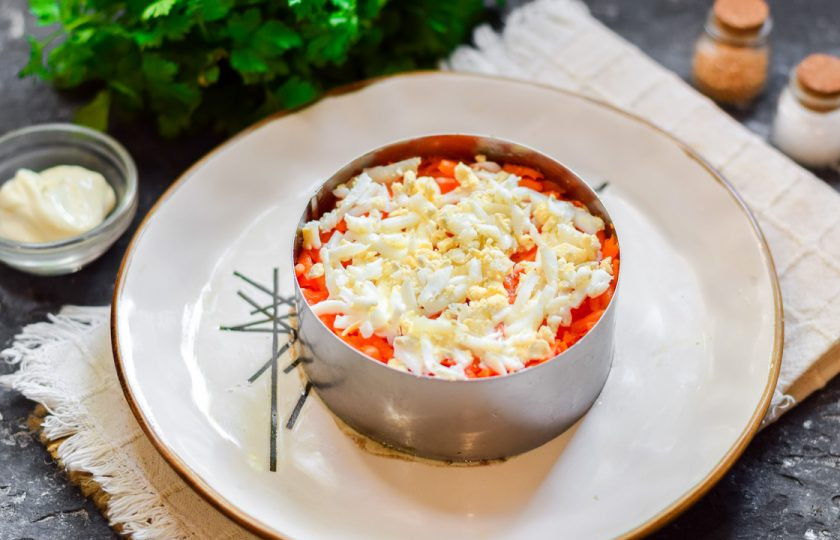 1. Этап. Салат Океан со шпротами: Поверх моркови выложите слой куриный яиц. Предварительно яйца отварите, почистите и натрите на средней терке.