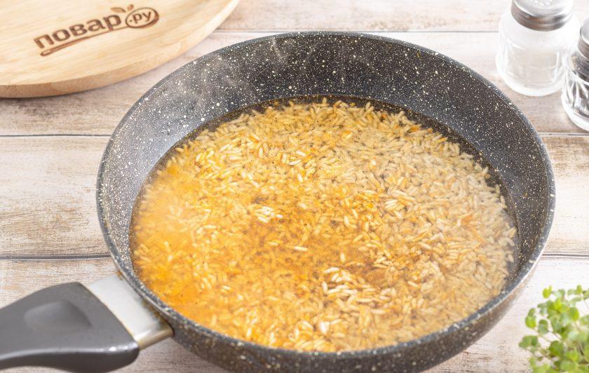 1. Этап. Рис жареный на сковороде: Влейте воду, все перемешайте, доведите до кипения и готовьте рис на небольшом огне под крышкой около 15 минут.