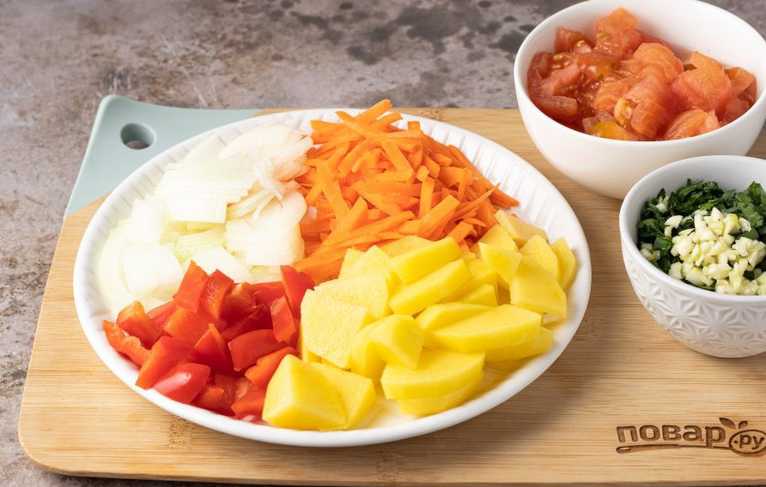 1. Этап. Суп с молодой фасолью: Порежьте репчатый лук полукольцами, морковь брусочками, а болгарский перец небольшими ломтиками. На помидорах сделайте надрез крест-накрест, ошпарьте их кипятком и снимите кожуру, затем порежьте кубиками. Чеснок вместе с зеленью мелко порубите. Картофель очистите и порежьте брусочками.