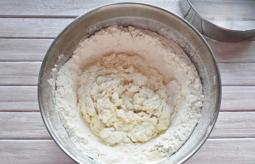 1. Этап. Момо с курицей: Начните замешивать тесто, размешивая вилкой и подсыпая муку с краев воронки в центр.