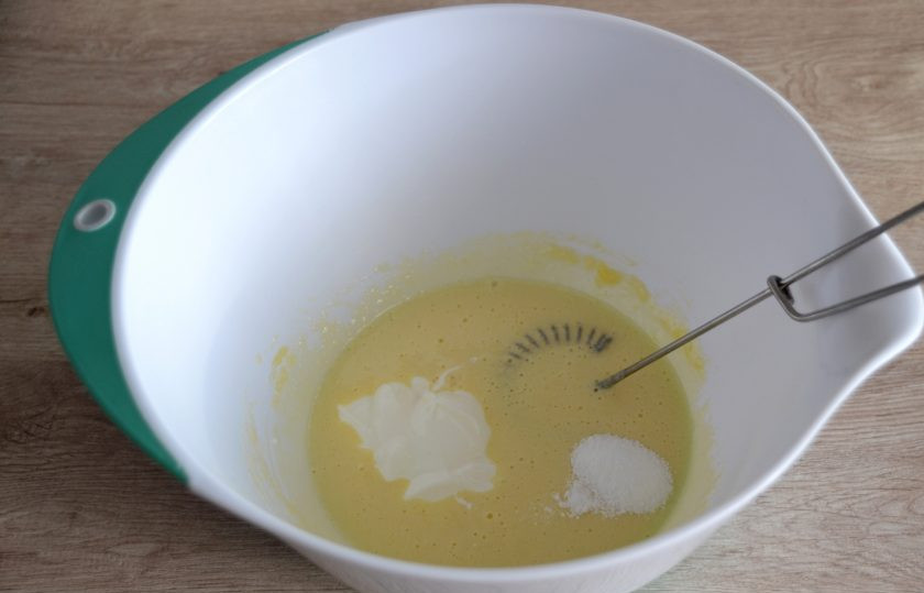 1. Этап. Шарлотка с абрикосами и вишней: Добавьте к желткам сметану и ванильный сахар, смешайте до однородной массы.