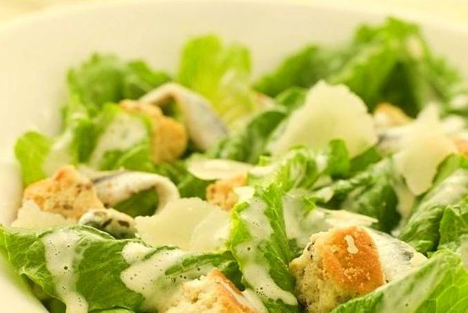 1. Этап. Салат Цезарь как в ресторане: Сверху выложить остывшие сухарики и полить остатками соуса. Посыпать тертым пармезаном и подать на стол.