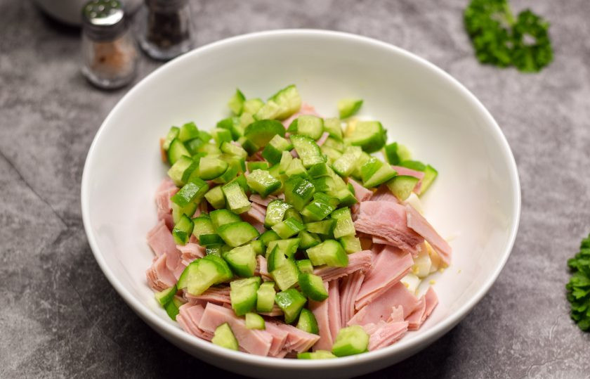 1. Этап. Салат Фантазия с яйцами и сыром: Свежий огурец сполосните и нарежьте небольшими кубиками. Добавьте огурцы в салат.