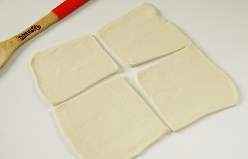 1. Этап. Рыба, запеченная в тесте в духовке: Слоеное тесто раскатайте на присыпанной мукой поверхности и разделите на четыре части.