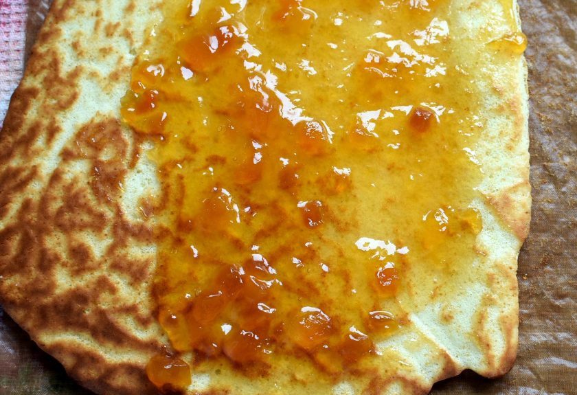 1. Этап. Рулет в кексе «Апельсиновый блюз»: Готовый бисквит аккуратно переверните на полотенце и снимите коврик. Смажьте апельсиновым джемом и закатайте в рулет. Заверните в полотенце и оставьте.