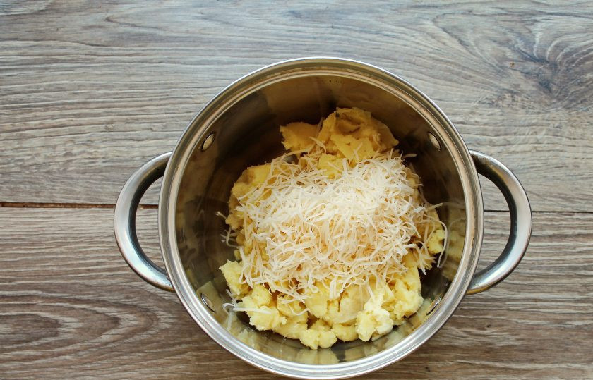 1. Этап. Картофельные зразы без начинки: Твердый сыр натрите на средней или мелкой терке и добавьте в кастрюлю с пюре.