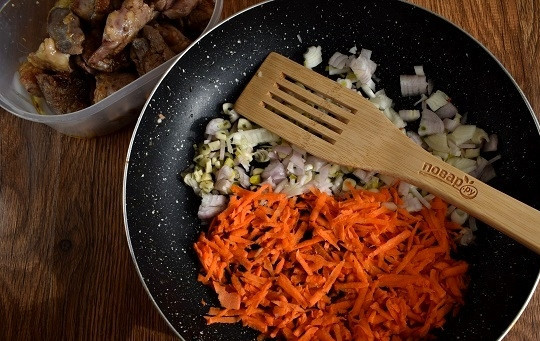 1. Этап. Курица с рисом и овощами по-каталонски: Мясо снимите со сковороды. На оставшемся масле пассеруйте измельченные лук, чеснок и тертую на крупной терке морковь до мягкости.