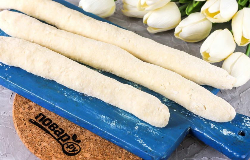 1. Этап. Ленивые вареники в мультиварке: Затем разделите тесто на несколько равных частей и скатайте из них длинные колбаски, подпыляя поверхность стола мукой.