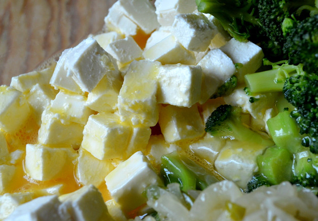 1. Этап. Киш с брокколи и сыром фета: Достаем фету. Достаем сыр целиком из пачки и аккуратно нарезаем на кубики. Перекладываем его в миску. Разбиваем туда 5 яиц, к ним же пойдут и оставшиеся белки. Из сковороды перекладываем лук в нашу начинку. Брокколи, соответственно, тоже отправляются туда же. Все перемешиваем, не кроша сыр.