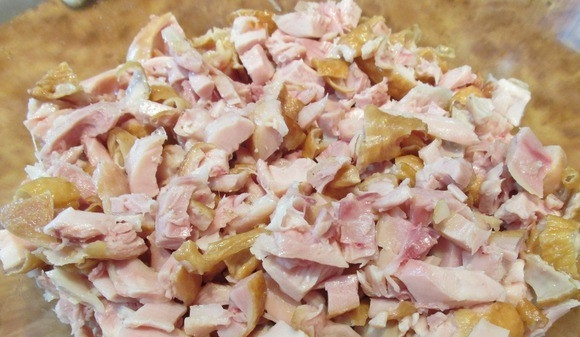 1. Этап. Салат из курицы с фасолью: Копченые куриные бедрышки разделайте, отделите мясо от кости. Нарежьте курицу вместе с кожей на небольшие кусочки равного размера.