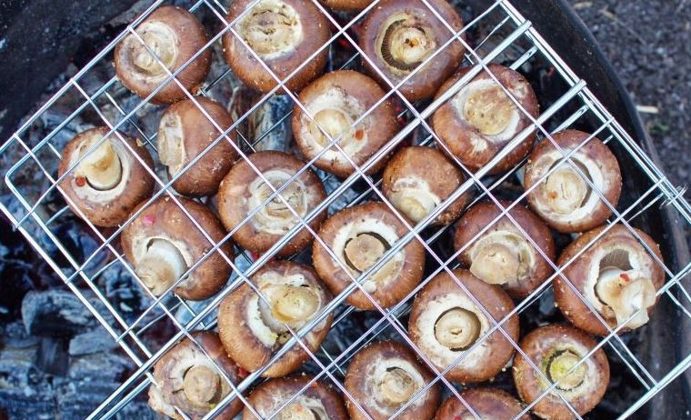 1. Этап. Шампиньоны на гриле на мангале: Замаринованные грибы выложите на решетку так, чтобы между ними были просветы. Обжаривайте грибы около десяти минут, периодически переворачивая со одной стороны на другую.